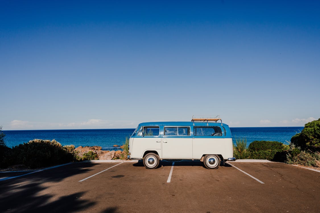 un mini van bianco e blu parcheggiato davanti al mare nomadi in normandia