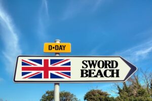 un cartello con una bandiera inglese indica la via per sword beach in normandia